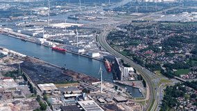 Aerial view of European shipping port full of renewable energy wind turbines, Nuclear Power Plants and fossil fuel distribution - With highway and train tracks running parallel - Ghent Belgium - Powered by Shutterstock - Get 15% off with code: PIKWIZARD15