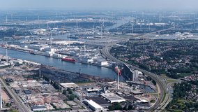 Aerial view of European shipping port full of renewable energy wind turbines, Nuclear Power Plants and fossil fuel distribution - With highway and train tracks running parallel - Ghent Belgium - Powered by Shutterstock - Get 15% off with code: PIKWIZARD15