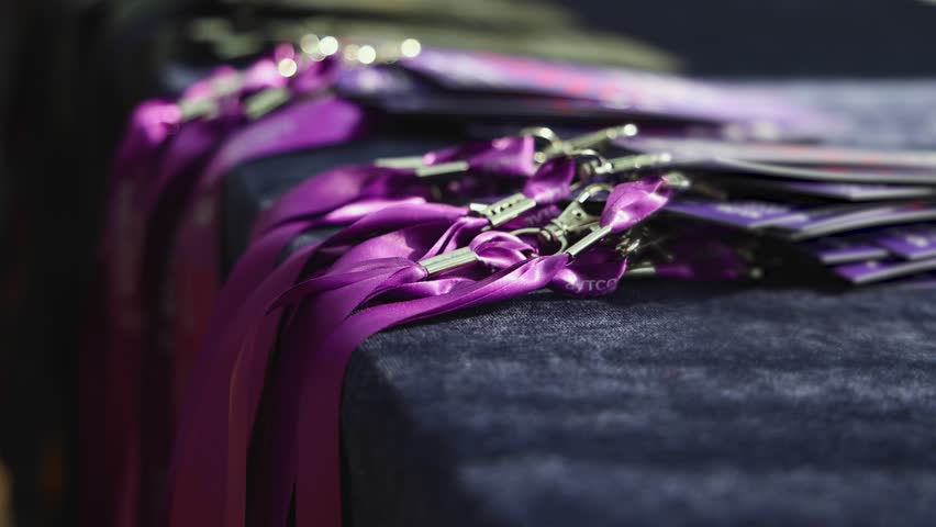 Process of checking in on conference congress forum event, registration desk table, visitors and attendees receiving purple violet lanyard with name badge and entry, and register electronic ticket