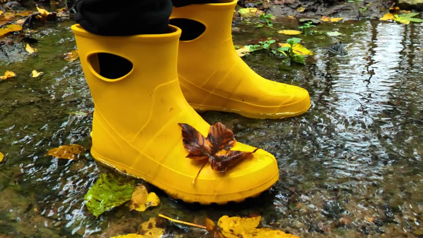 Autumn weather . Shoes for autumn.Feet in rubber boots splash through a puddle. Autumn damp atmosphere. 4k footage