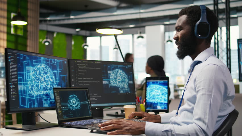Computer scientist in office integrating AI machine learning systems to streamline workflows, earing headphones. African american man uses artificial intelligence on devices, listening music, camera A