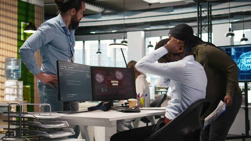 Programmer in office requesting help from coworkers to fix critical error warning. IT employee and colleagues brainstorming how to fix computer bug affecting systems, camera A