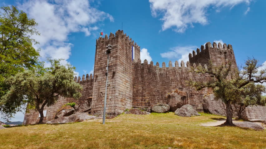 The Medieval Castle of Guimaraes crowns a granite outcrop with imposing keep corner towers and crenellated curtain walls dominating Guimaraes, Portugal
