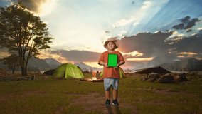 Asian Boy With A Hat Smiling And Showing Green Screen Tablet. Boy Researcher Examines Something While Tent Camp Lakeside, Travel Tourism Adventure Concept, Full Body - Powered by Shutterstock - Get 15% off with code: PIKWIZARD15