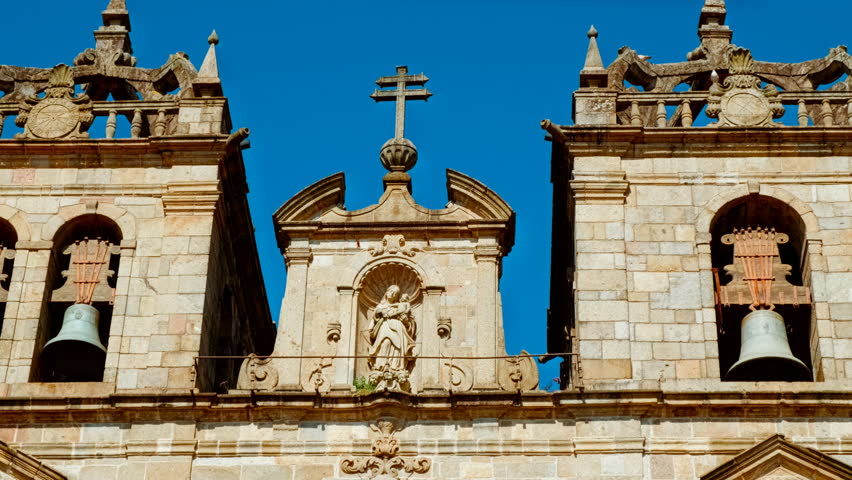 Close up reveals weathered granite carvings of Braga Cathedral exteriors with Manueline motifs cherub faces and stone pinnacles catching afternoon light in Braga, Portugal
