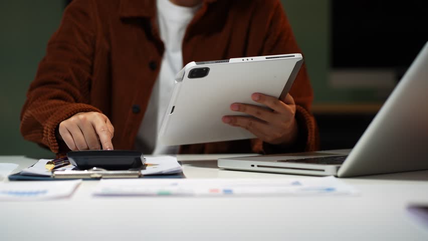 Hand take notes and use the calculator with calculations about the expenses at the office.	