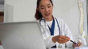 Doctor conducts video consultation, explains spine surgery using anatomical model, explaining symptoms and treatment to patients. - Powered by Shutterstock - Get 15% off with code: PIKWIZARD15