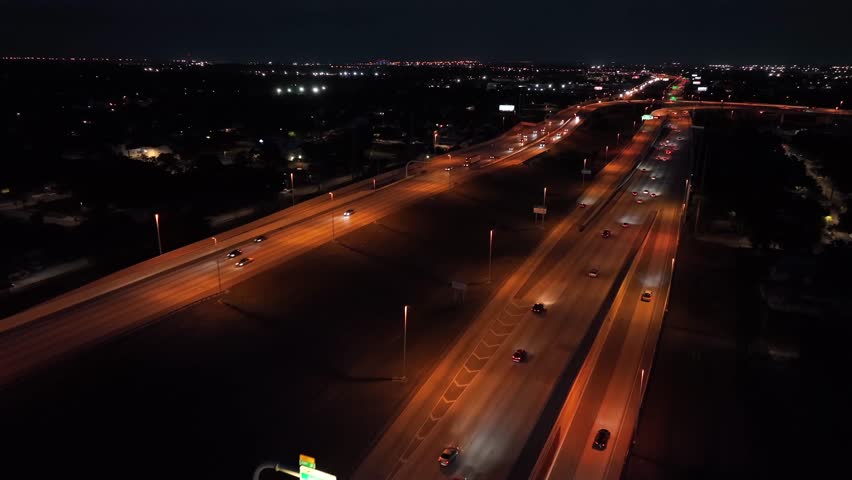 Orange illuminated interstate highway in Florida with busy traffic at night. Aerial flyover tracking shot. Many cars speeding on road at midnight. Tampa, Florida.