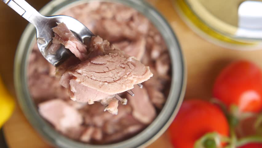 fork pick tuna from a caned tuna container 