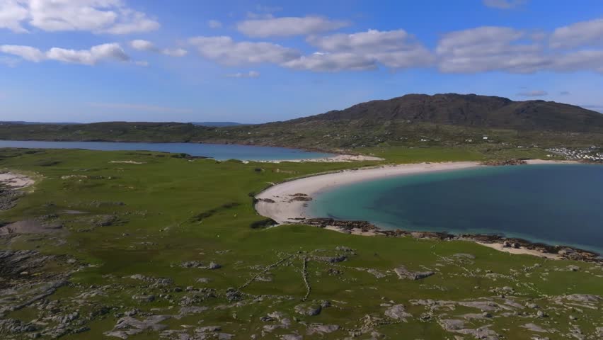 Dog's Bay Beach, Roundstone, Connemara, County Galway, Ireland, May 2025. Drone flyover aerial view above twin crescent beaches, Connemara landscape, wild Atlantic way and Irish summer coast.