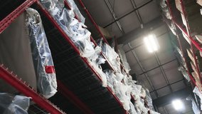 Camera drifts beneath stacked pallets, tilting up to packed shelves in distribution center - Powered by Shutterstock - Get 15% off with code: PIKWIZARD15