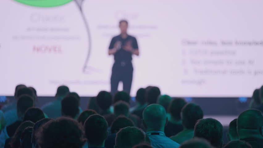 Conference speaker delivering a presentation to attendees with visuals creating an engaging professional atmosphere.