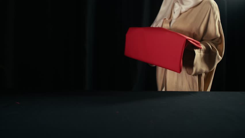 A veiled woman sewing the Turkish flag with a needle and thread