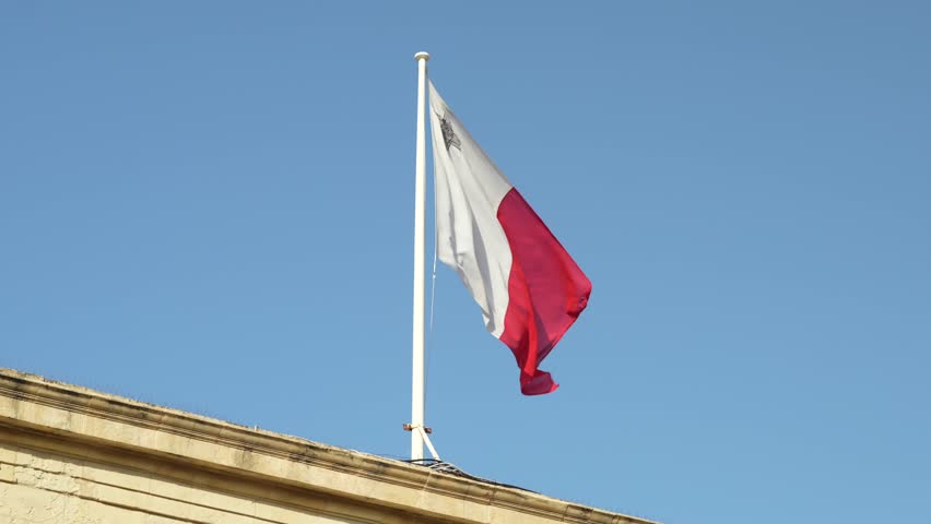 Maltese Flag waving in the wind, in slow motion, on a sunny day with blue sky