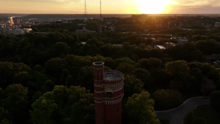 Aerial view of the tower bathed in the warm glow of the setting sun, with cityscape peeking through the trees, Cincinnati, Ohio, United States.