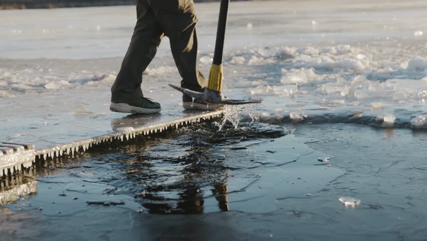 A man crushes ice as golden sunlight illuminates the crystalline frozen water