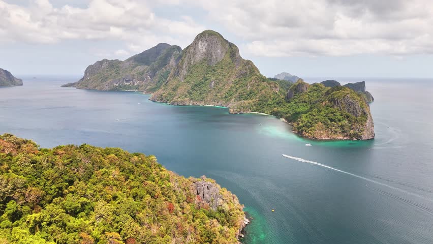 Aerial perspective of El Nido, Palawan, Philippines featuring limestone cliffs, lush green landscapes, and turquoise coastal waters with boats gliding through the serene tropical sea