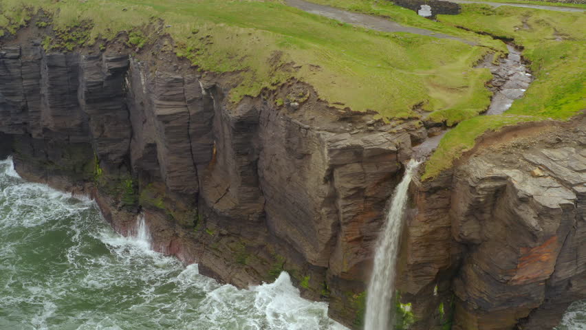 Aerial static shot of a cliff edge with a waterfall in the west of ireland. Moher