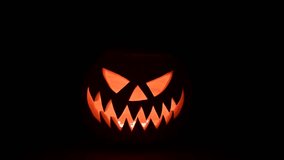 Moving glowing jack-o'-lantern lit from inside on black background. Halloween concept. UHD 4k video - Powered by Shutterstock - Get 15% off with code: PIKWIZARD15