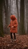 Girl in orange jacket with a spooky carved pumpkin head dancing on Halloween in the misty autumn forest. Fall holiday concept - Powered by Shutterstock - Get 15% off with code: PIKWIZARD15