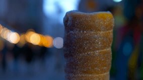Woman holding trdelnik at christmas market. Hand holding freshly baked, warm chimney cake amid twinkling christmas market lights, showcasing traditional hungarian street food with bokeh background - Powered by Shutterstock - Get 15% off with code: PIKWIZARD15