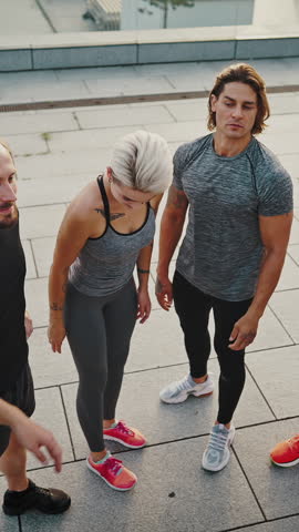 Multiracial group of athletes, men and women in sports uniforms doing a high five after completing a morning workout together.
