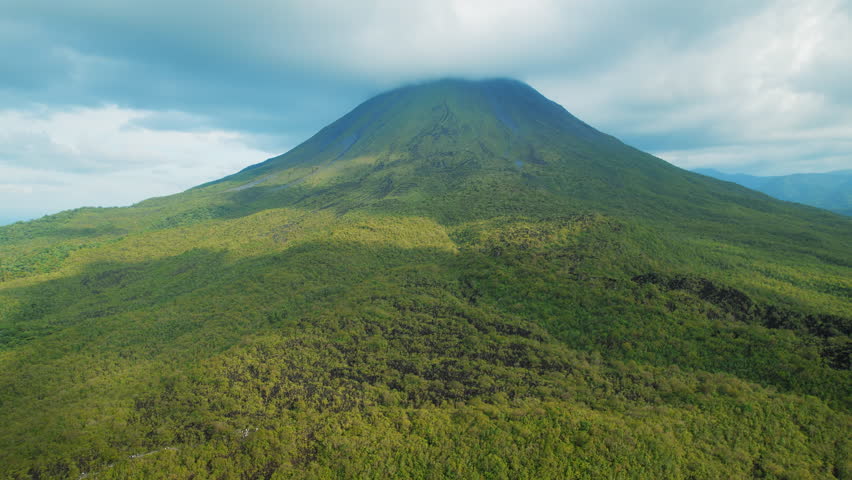 Arenal Volcano surrounded by dense green forest and lava fields in Costa Rica