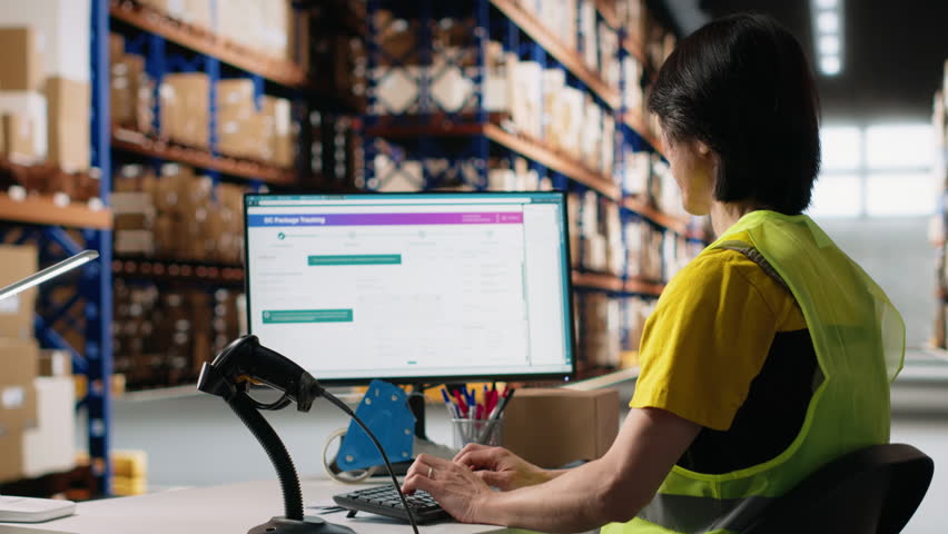 Asian male worker scanning shipment labels and tracking numbers in a distribution hub, ensures order management in fulfillment center. Using a scanner for transportation details. Camera B.