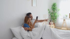 Diverse young man and woman watching movie together in the morning. Attractive new marriage couple lying down on bed, feel happy and relax while watching series on television after wake up in bedroom. - Powered by Shutterstock - Get 15% off with code: PIKWIZARD15