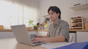 Asian attractive man freelancer using laptop device working in house. Handsome male student chatting and typing on computer notebook to communicate online with technology in cozy kitchen at home. - Powered by Shutterstock - Get 15% off with code: PIKWIZARD15