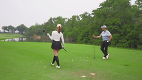 Asian young couple golfer swing clubs together on a scenic golf course. Attractive people enjoy fun game outdoor recreation and light exercise while practicing under the guidance of trainer in course. - Powered by Shutterstock - Get 15% off with code: PIKWIZARD15