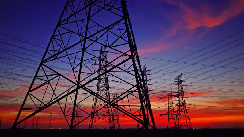 High voltage power tower and power lines with beautiful sky clouds at night