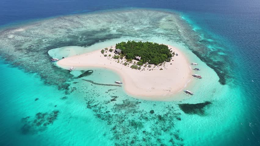 Drone glides toward the heart-shaped Patawan Island, revealing white sand beaches, lush vegetation, and coral-rich waters in the Sulu Sea, near southern Palawan, Balabac, Philippines