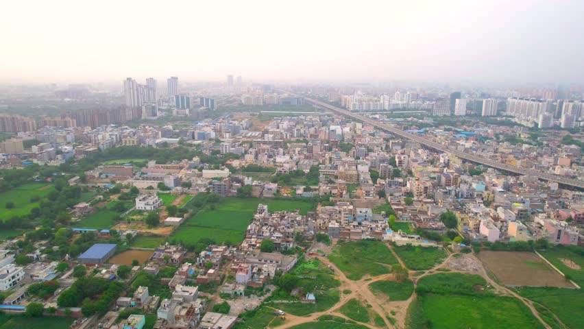 Aerial drone shot flying over densely packed houses homes, buildings with sohna expressway passing through the middle showing cityscape of gurgaon delhi