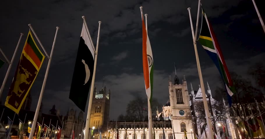 Nighttime detail and panoramic shot of Commonwealth flags displayed around the perimeter of Parliament Square Garden in central London, Great Britain