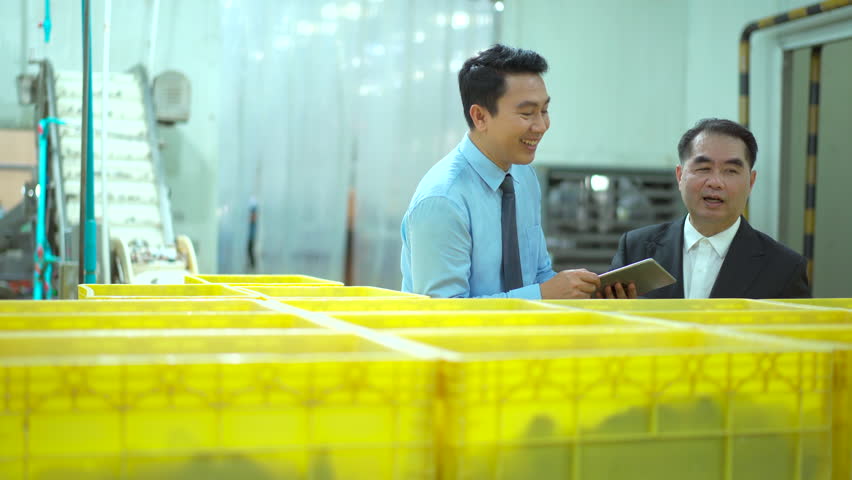 Two Asian businessmen walk through a seafood and canned fish processing factory, inspecting raw materials and shaking hands. The moment represents partnership, and business collaboration. - Powered by Shutterstock - Get 15% off with code: PIKWIZARD15