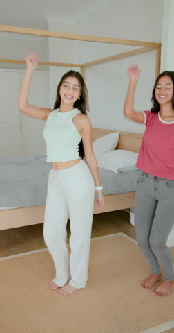 Diverse female friends dancing for fun after beat drop in bright bedroom with canopy bed. Cheerful, friendship, choreography, home, lifestyle, upbeat, vertical video