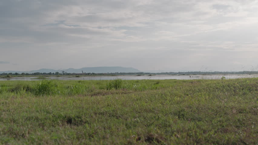 Person Cycling Past Green Grassy Field