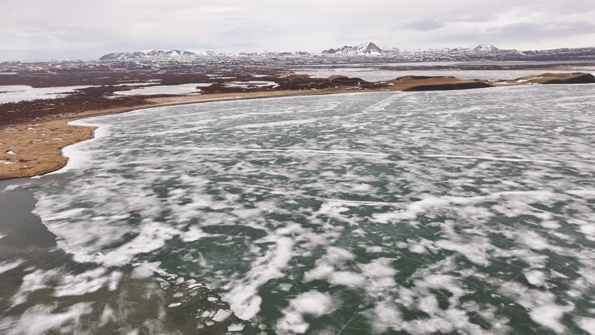icy Lake Mývatn with snowy terrain and volcanic mountains near Skútustaðir village. Reykjahlíð, Iceland