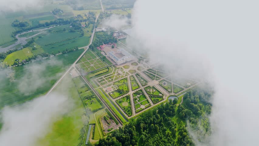 Elegant aerial of historic French-style palace gardens glowing through clouds