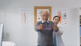  Asian female doctor or physiotherapist guides her elderly male patient through shoulder muscle exercises using a medical resistance band. She carefully monitors posture and offers hands-on support - Powered by Shutterstock - Get 15% off with code: PIKWIZARD15
