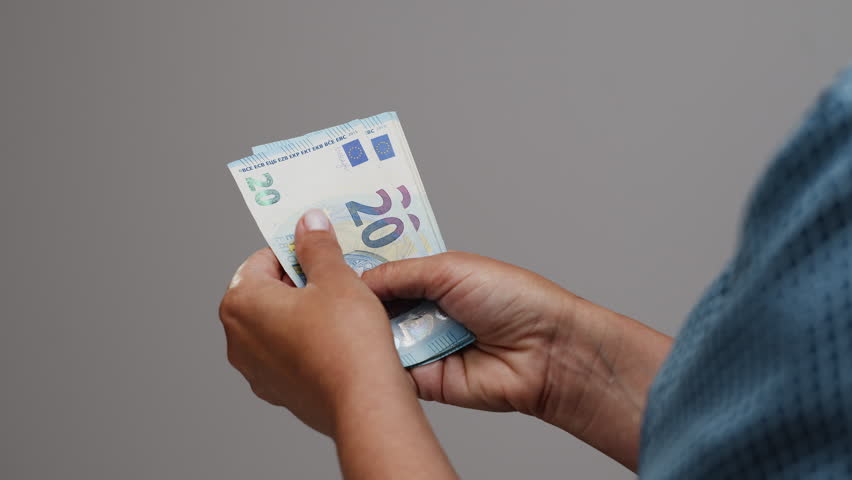 Female hands count euros while sitting at a table. Utility bills and receipts on the table. The process of calculating a household budget. Or the process of calculating the income of a small business.