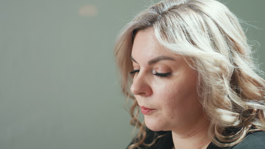 close up of professional woman holding phone between ear and shoulder during phone call, multitasking in quiet office environment with blurred background showing minimal movement