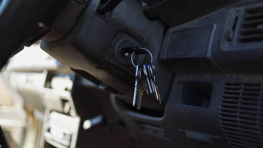 Closeup detail: Hand turns key in vehicle ignition to start truck