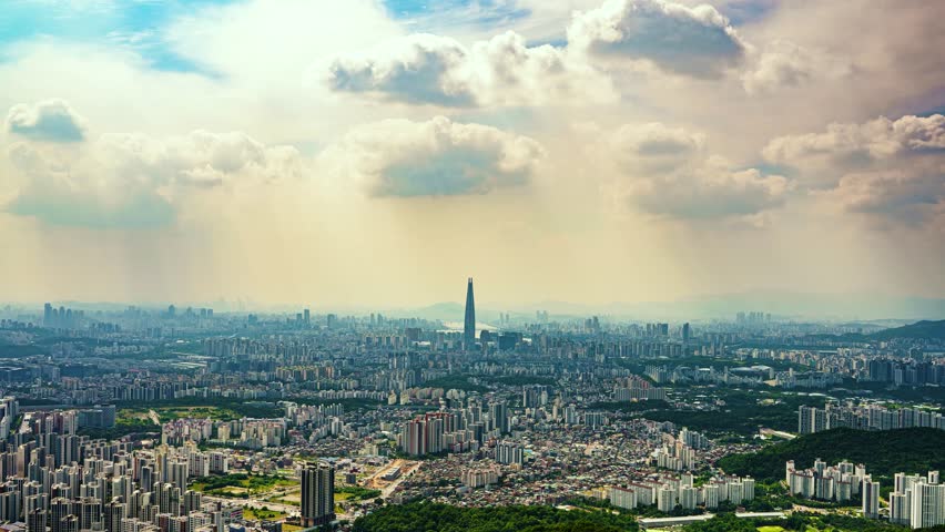 A stunning zoom-in timelapse captures moving clouds and dramatic light over the sprawling metropolis of Seoul, focusing on the iconic Lotte World Tower, as viewed from Namhansanseong fortress.