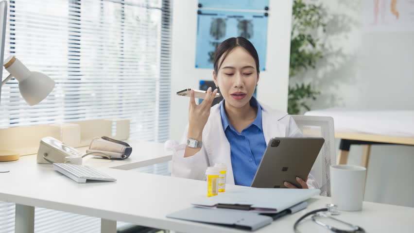 Portrait of an Asian female doctor using a smartphone in a hospital corridor, interacting with a virtual assistant or AI chatbot. She reviews health data via smart mirror technology, embracing future