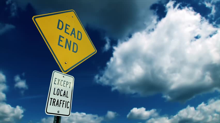 Low-angle shot of a yellow "Dead End" street sign with a secondary sign reading "Except Local Traffic" beneath it. Captured against a vivid blue sky with soft clouds, ideal for traffic or road themes.