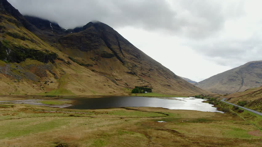 Breathtaking aerial view of Glen Coe valley in Scottish Highlands, showcasing its stunning mountains, tranquil lake, and vast landscape