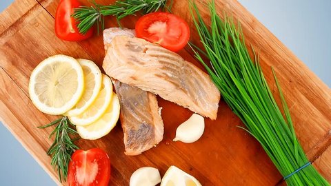 savory sea fish entree : roasted salmon fillet with green onion red cherry tomatoes pieces glass pepper grinder rosemary twigs and lemon on wooden board 1920x1080 intro motion slow hidef hd