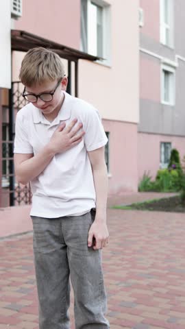 Teenager feels sharp pain in heart after school bullying. Concepts of heart failure, stress and panic attack. Vertical video.